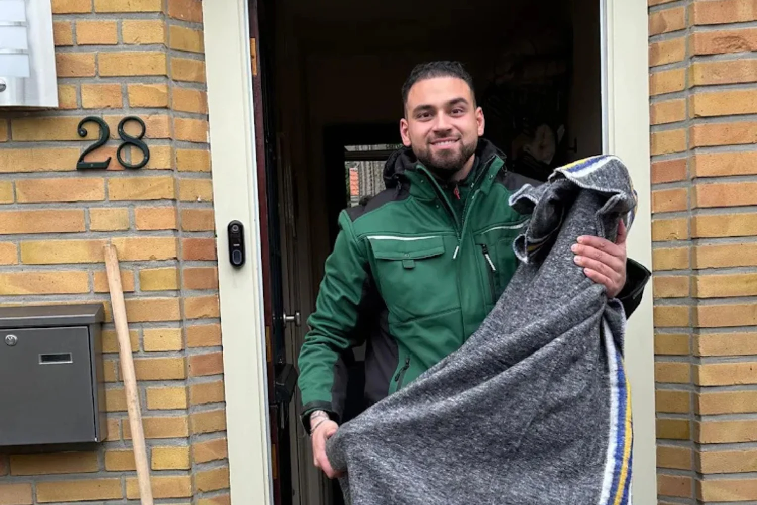 Een verhuizer met beschermmateriaal bij een voordeur