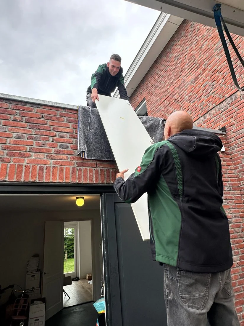 Twee verhuizers begeleiden een verpakt meubel