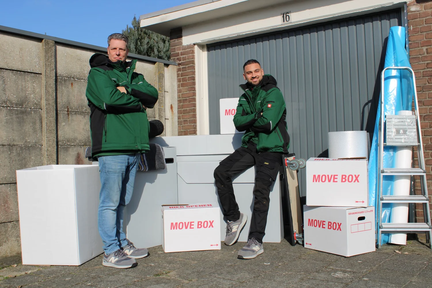 Twee medewerkers bij de verhuiswagen en verhuisdozen